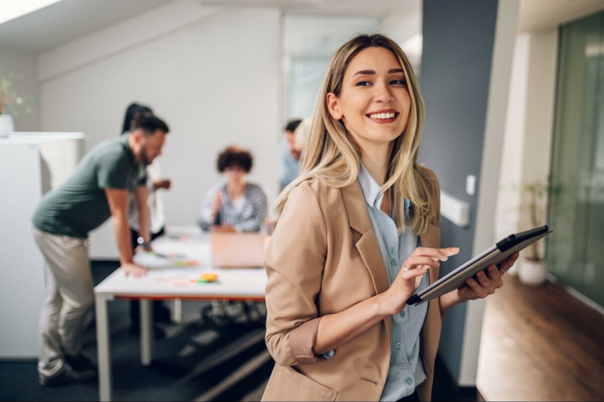 Woman in work environment holding a tablet.